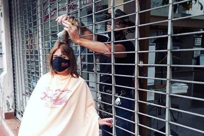 Contra lockdown, dono de salão viraliza com corte de cabelo pela grade